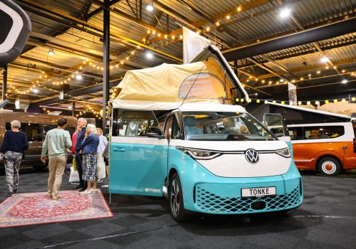 Turquoise Volkswagen-camper met hefdak op kampeerbeurs