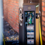 Detailbeeld van een open laadpaal met zichtbare bekabeling en elektronische componenten.
