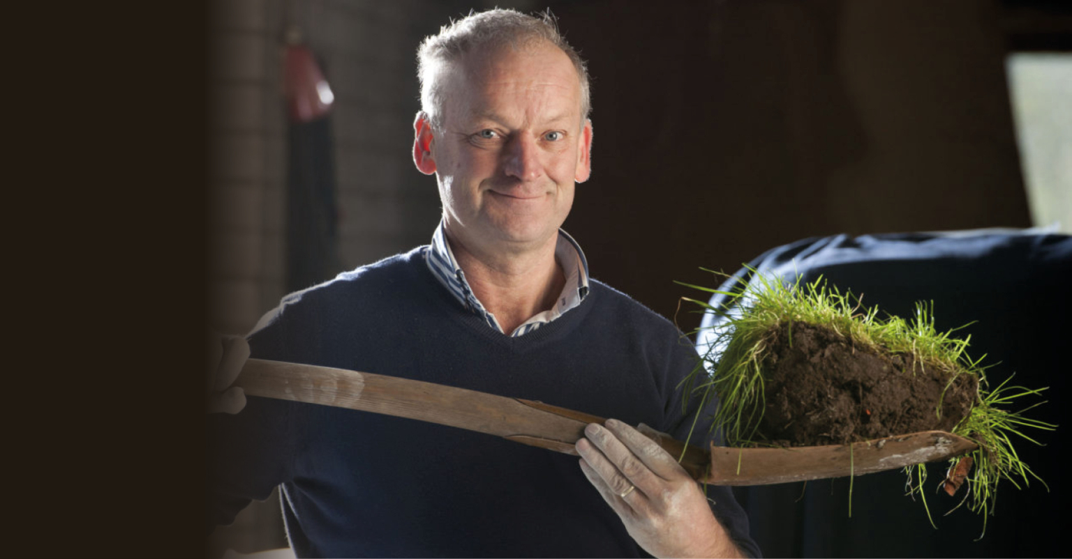 Man houdt oud gereedschap met graszode vast