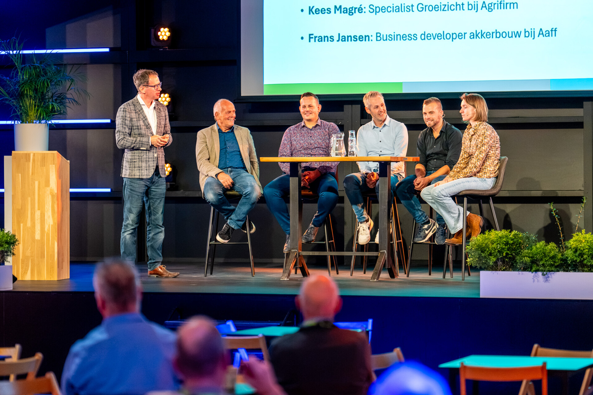 Panelgesprek met zes sprekers op een podium