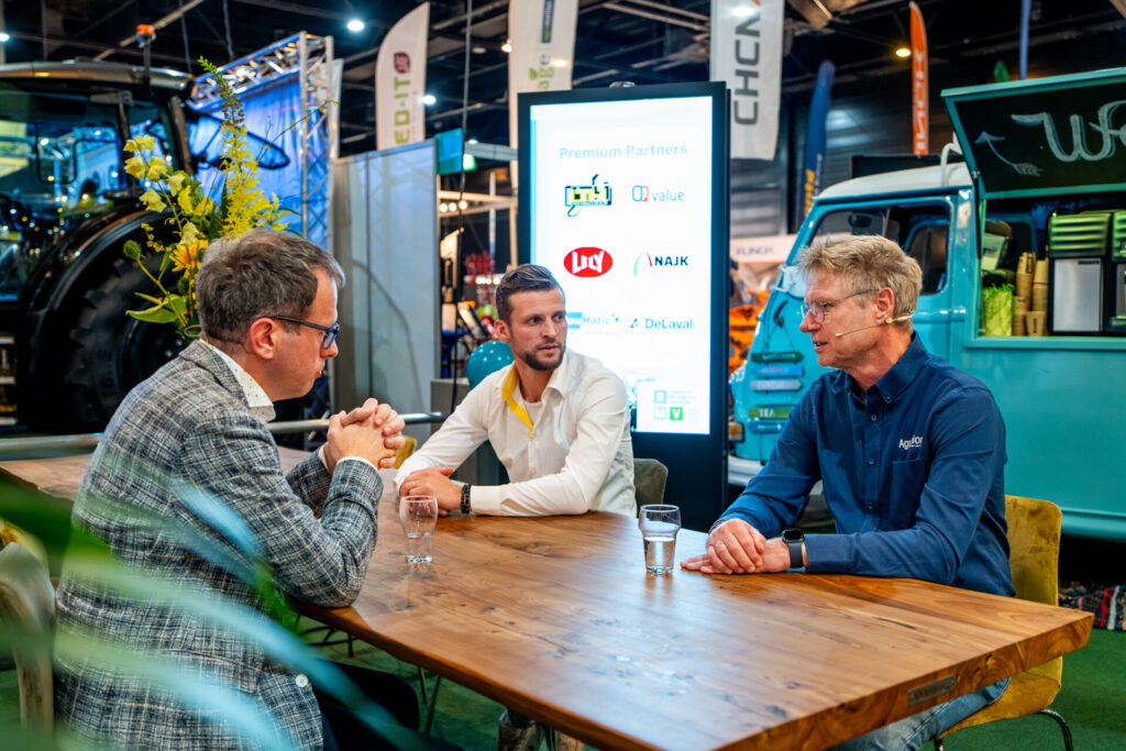 Drie mannen overleggen aan tafel op landbouwbeurs