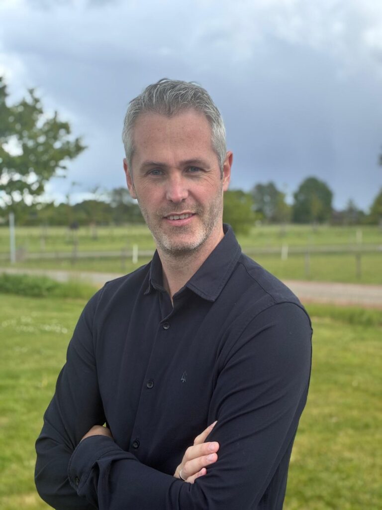 Man met gekruiste armen in groen landschap