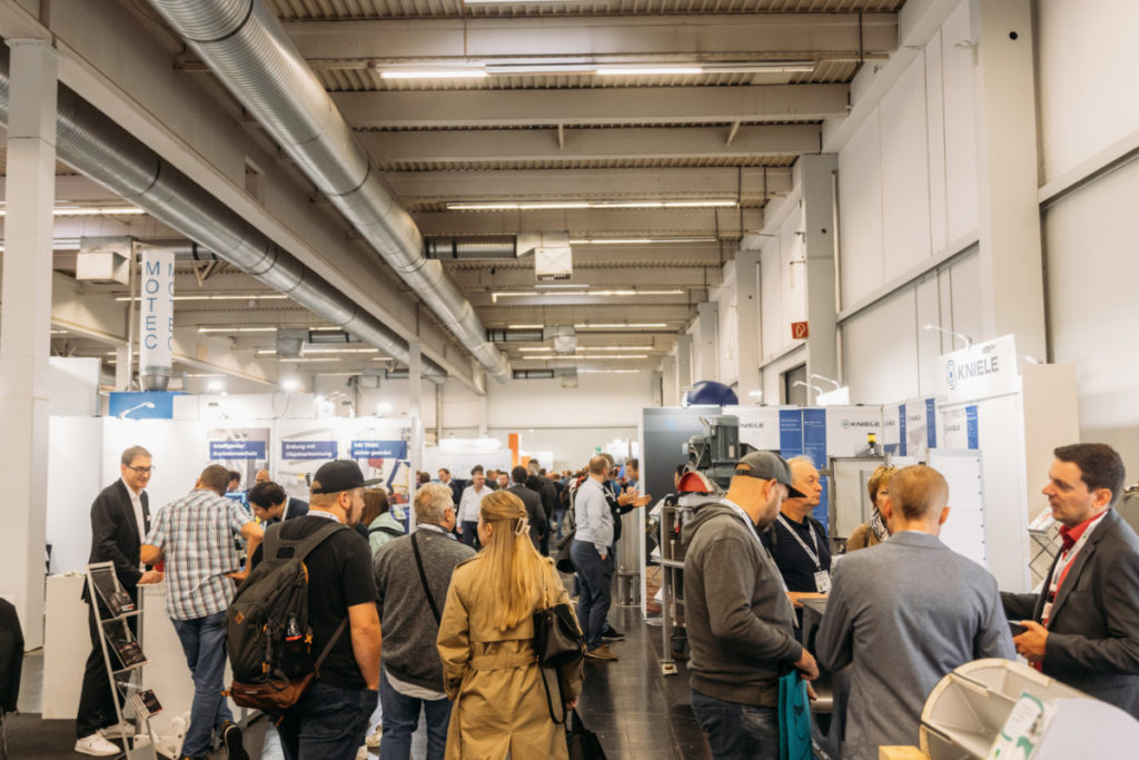 Messegang mit Menschenmenge und Ständen