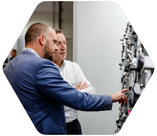 zwei Männer stehen an Maschine und unterhalten sich