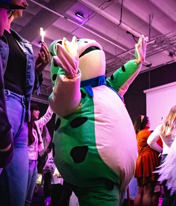Frog mascot dancing in a crowd at Comic Con.