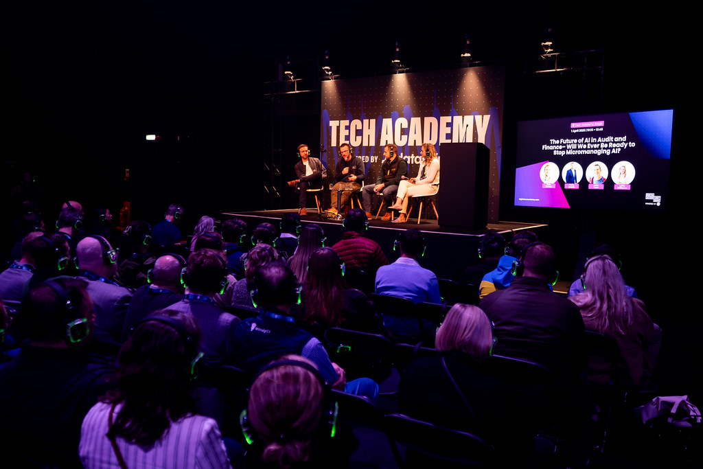 A stage at an event, with a panel of speakers discussing