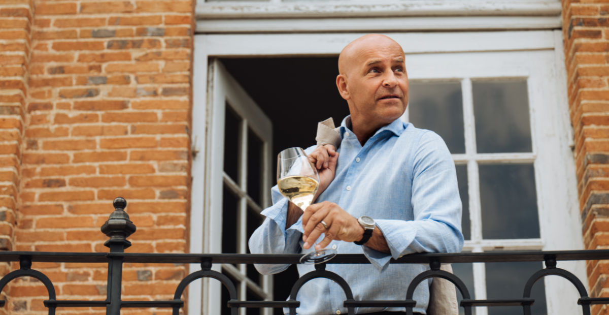 Richard Juhlin håller ett glas champagne på balkong