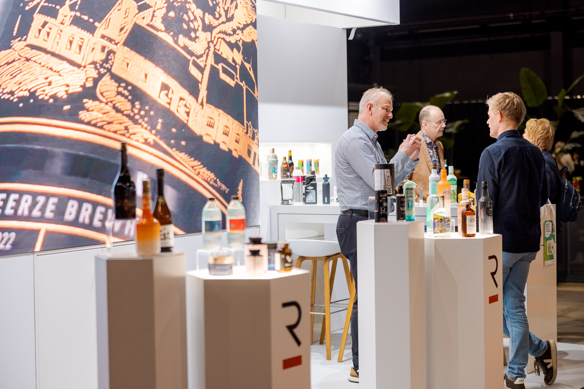 Bezoekers bekijken drankflessen op een beursstand
