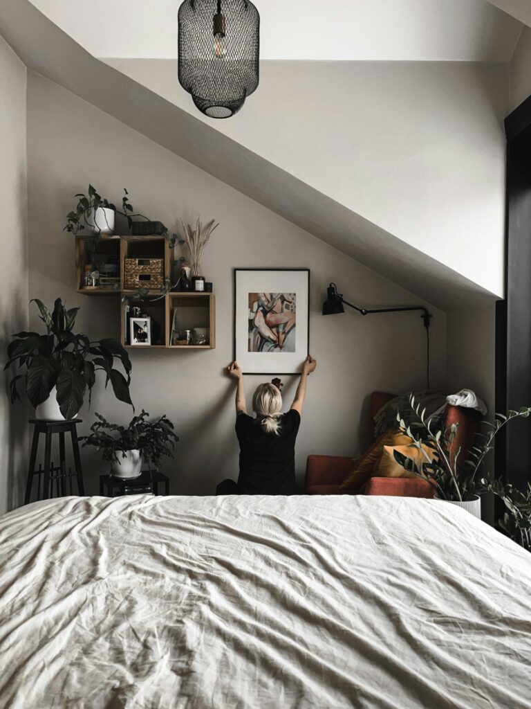 Vrouw hangt schilderij op in slaapkamer