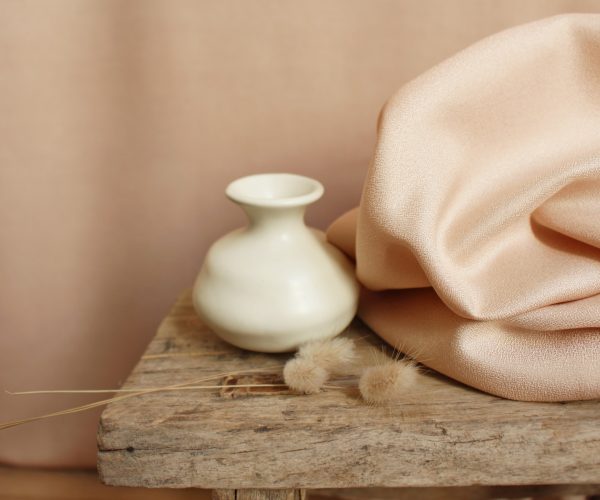 Houten bank met drie strohalmen erop, een schaaltje en een doek