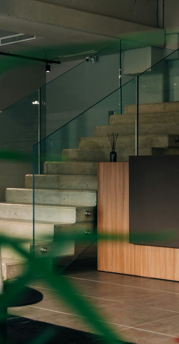 Een trap in beton met glazen leuning midden in de living