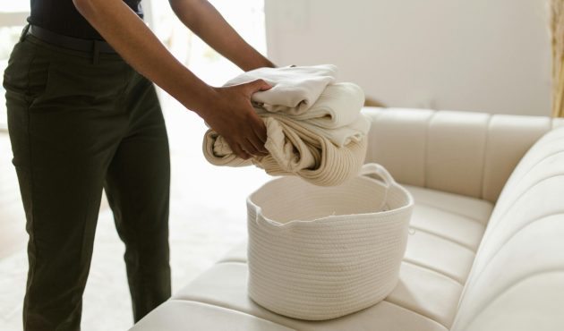 Een witte wasmand op een witte zetel. Hierin doet een vrouw haar was.