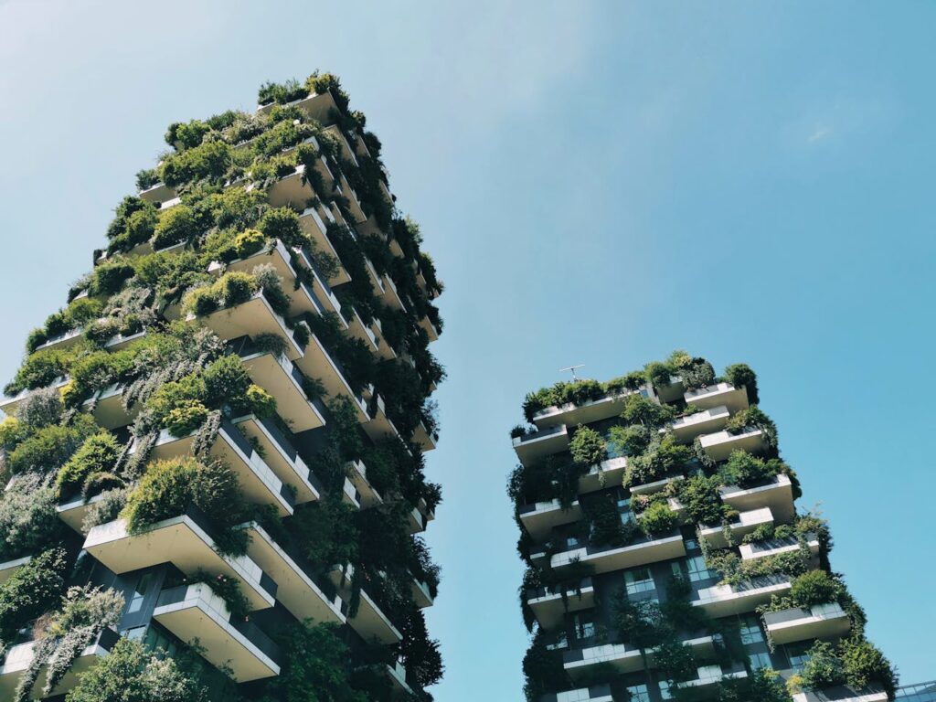 Twee skyscrapers vol groene bomen en struiken op de gevels en de balkons. Op de achtergrond een blauwe lucht.