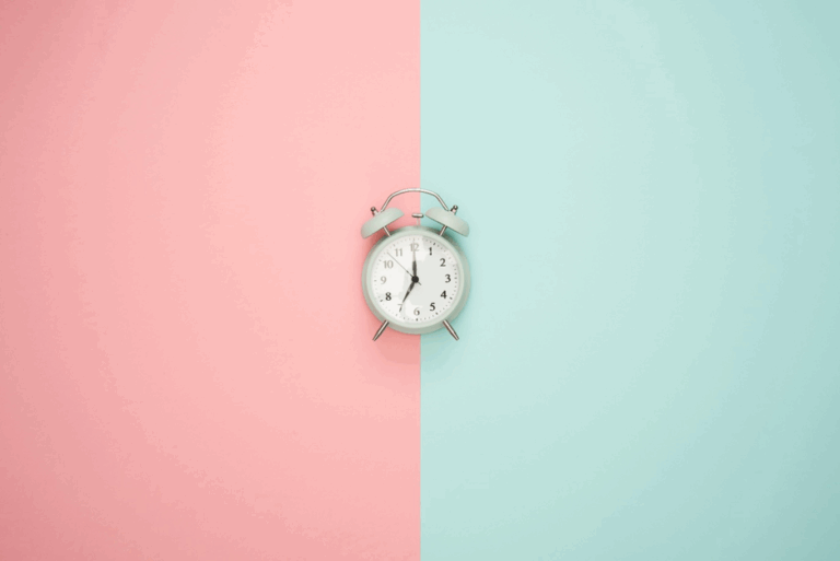 wekker die ligt op pastel roze en blauwe achtergrond
