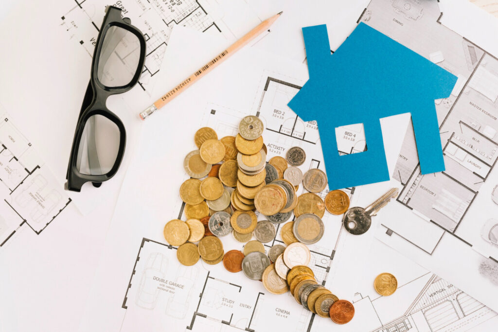 Werkblad met daarop een bril, de grondplannen van een woning, een icoon van een huis en geld.