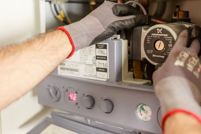 Handen die aan een boiler aan het werken zijn.