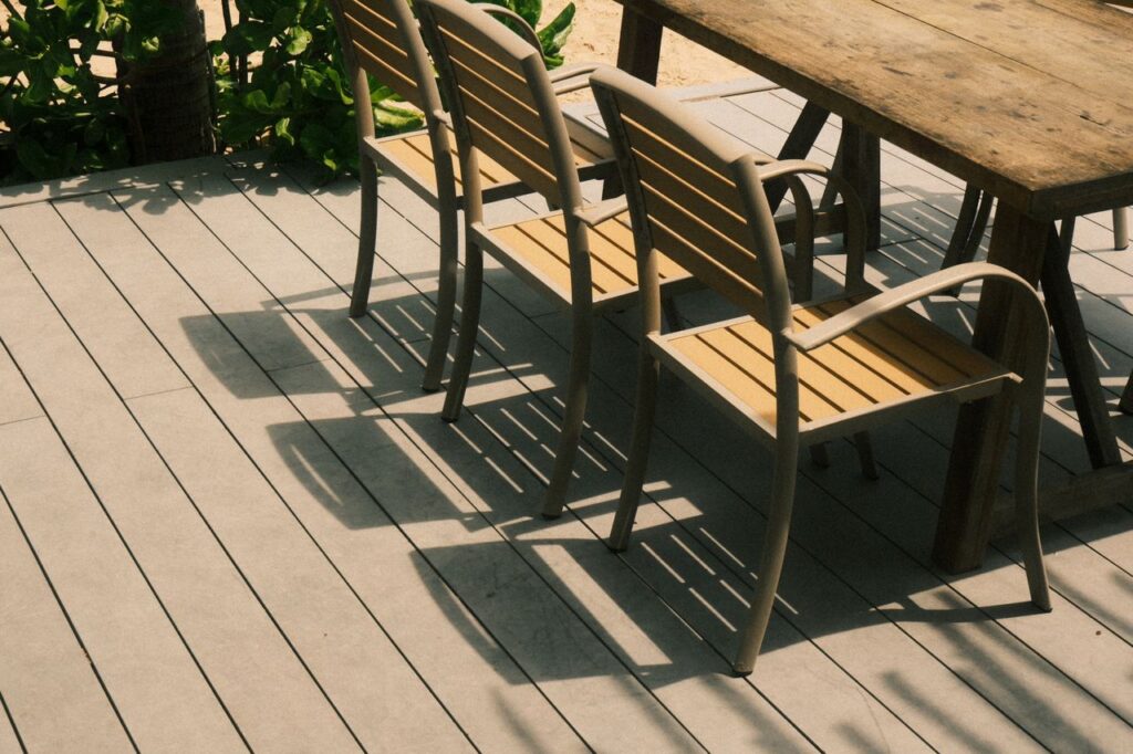 Terras met composiettegels die eruitzien als hout. Op het terras bevinden zich een tafel en 3 stoelen uit hout.