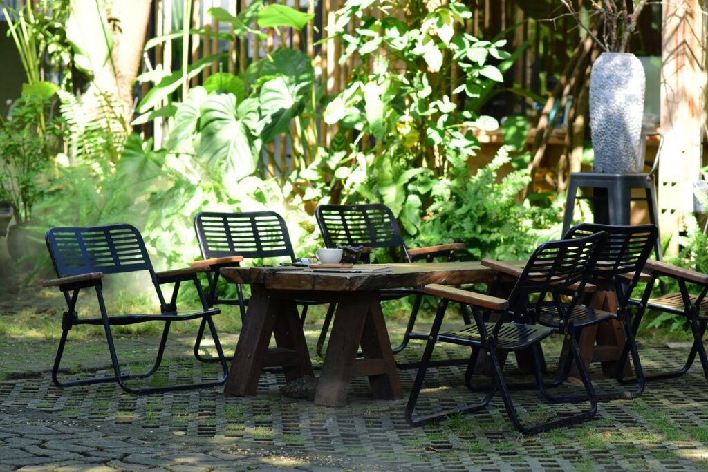 Tuinterras met veel groen op de achtergrond en een set van 6 lage stoelen en tafel.