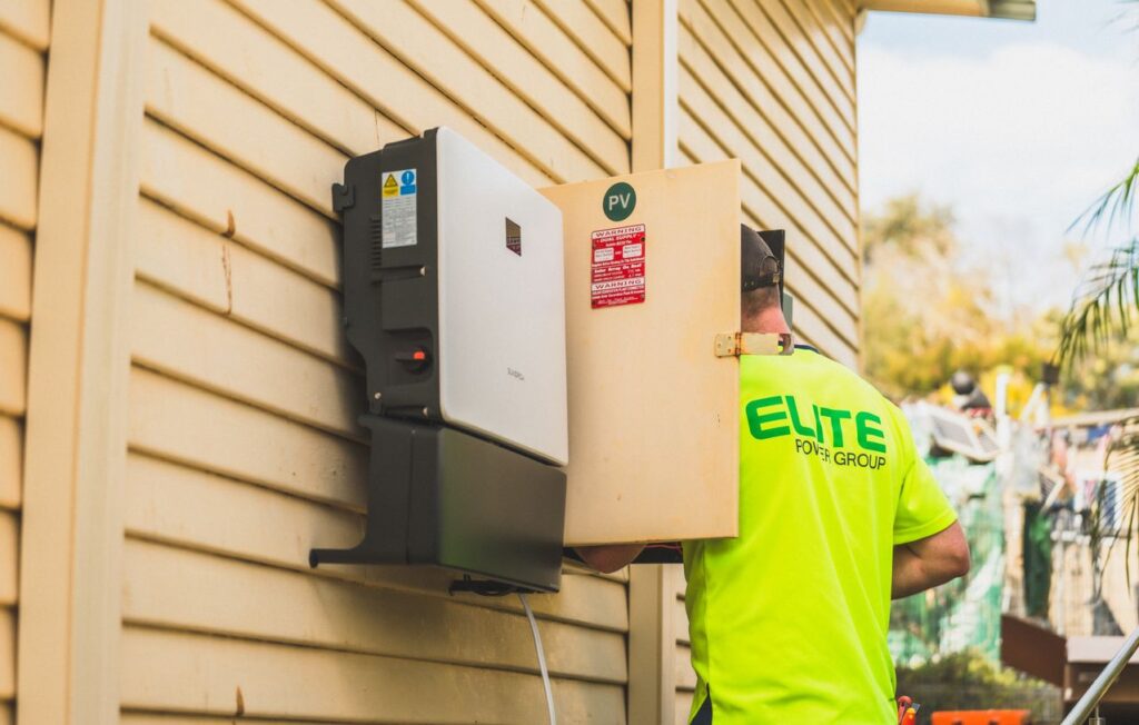Plug & play thuisbatterij op de gevel van een huis met een elektricien ernaast.
