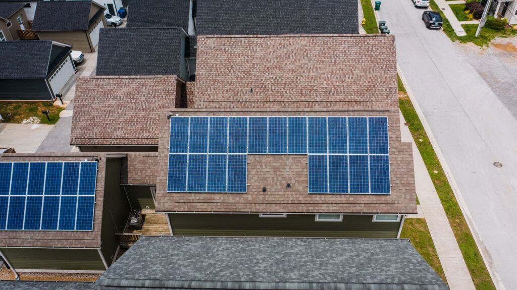 Foto van twee daken van huizen met zonnepanelen erop.