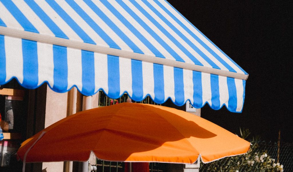 Knikarmscherm in het blauw en wit met daaronder een parasol.