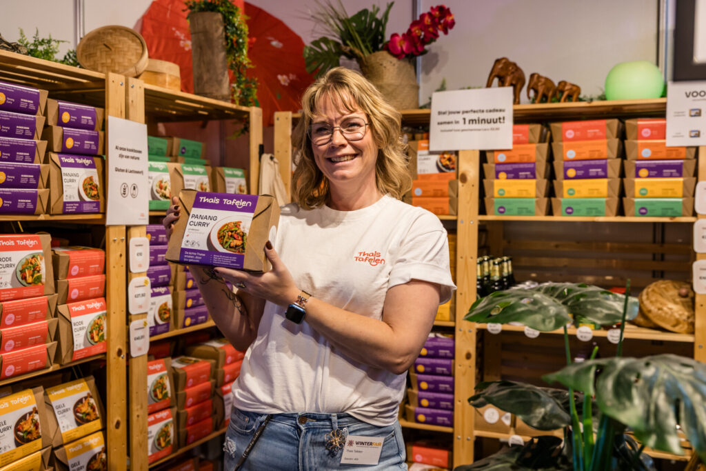 Medewerkster toont Panang-currymaaltijd op beursstand