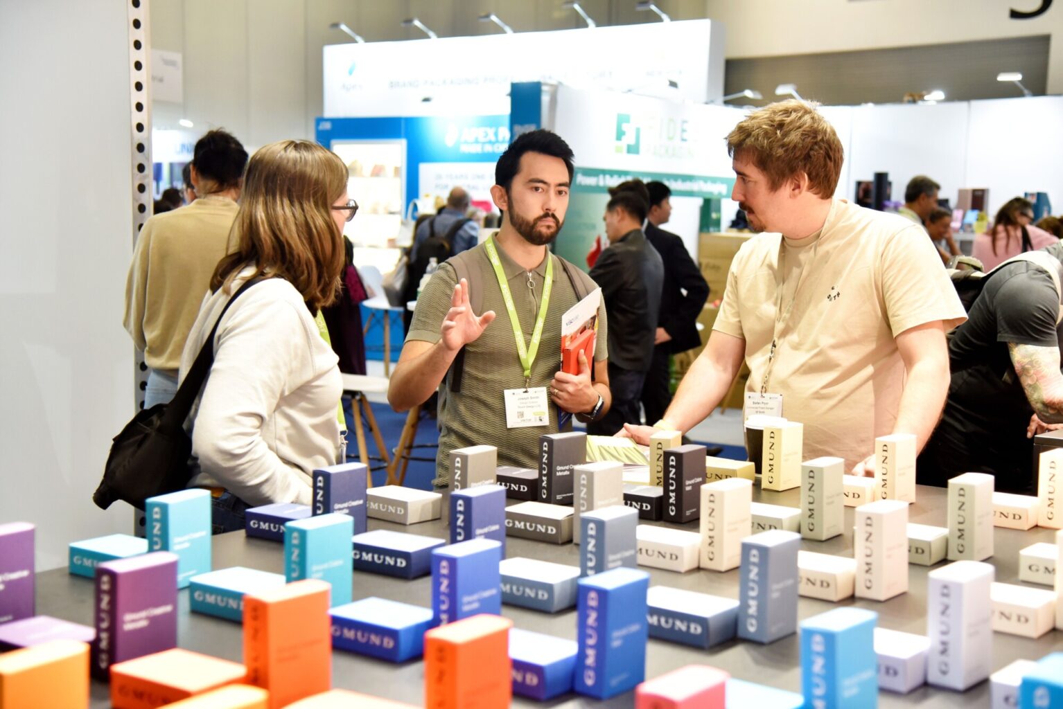 Visitors discussing premium packaging solutions and exploring carton samples with an exhibitor at London Packaging Week.