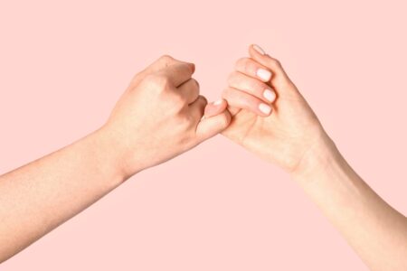 Two hands linking little fingers in a pinky promise gesture, symbolising trust and commitment.
