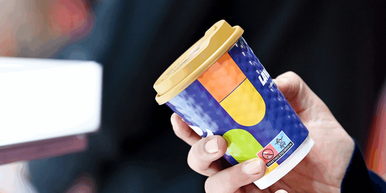 Hand holding a recyclable takeaway cup with a patterned design at Packaging Innovations & Empack.