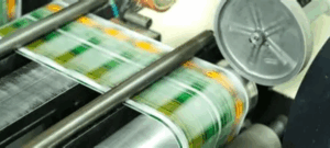 High-speed printing press producing colourful packaging labels on a continuous roll.