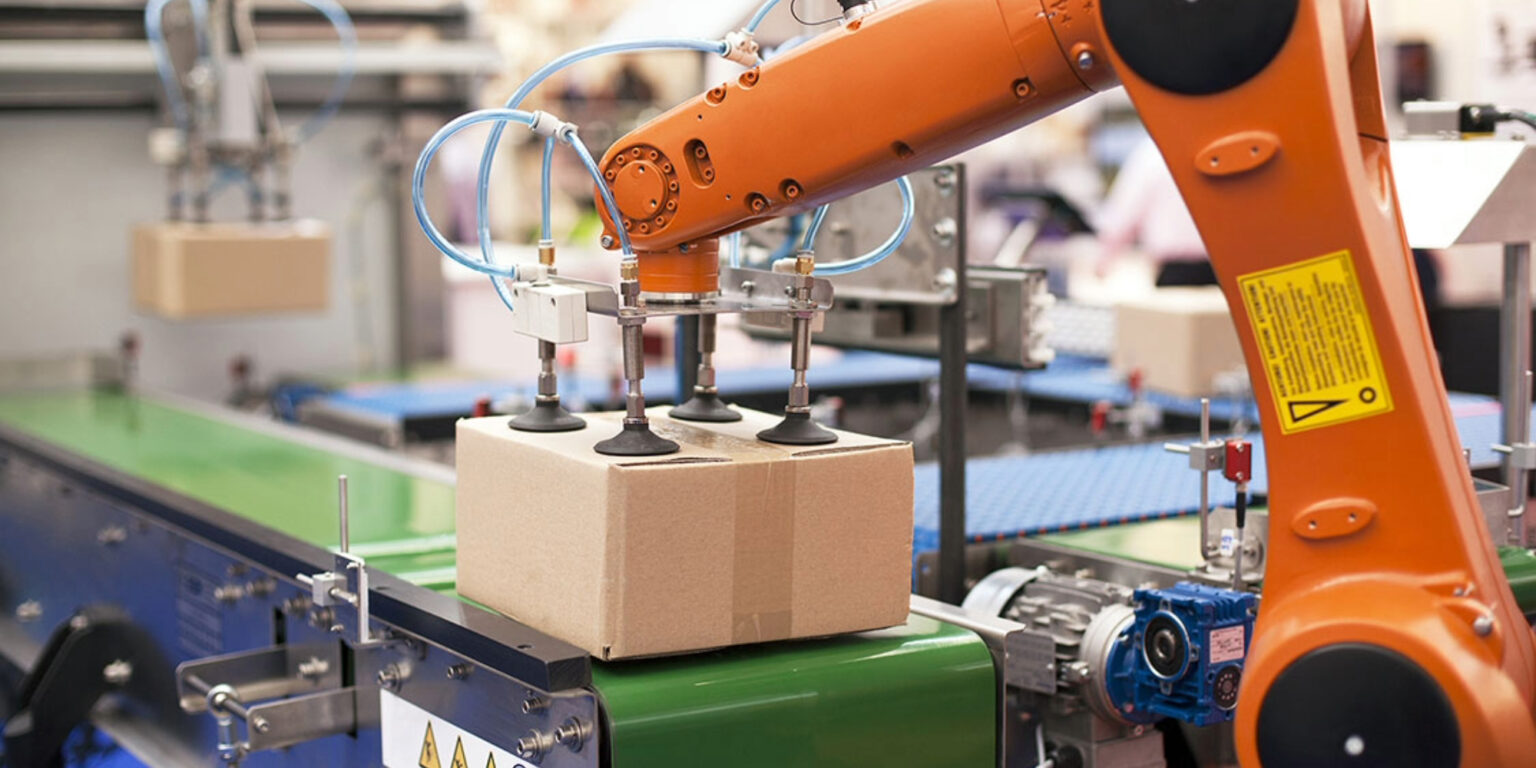 Industrial robot lifting a cardboard box on an automated packaging line