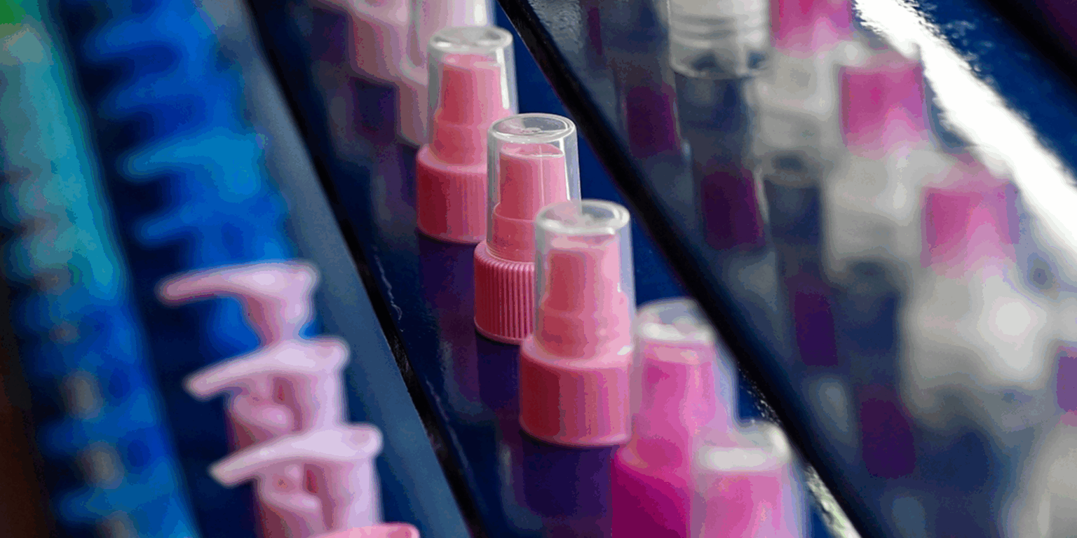 Dispensing pump and spray closures arranged in rows on display.