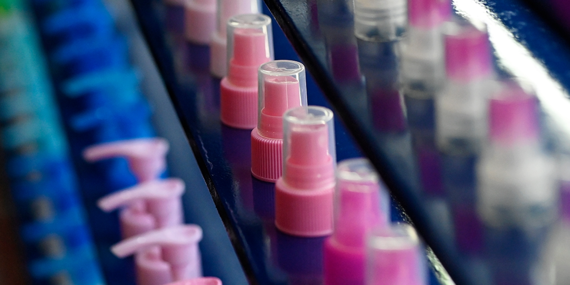 Dispensing pump and spray closures arranged in rows on display.