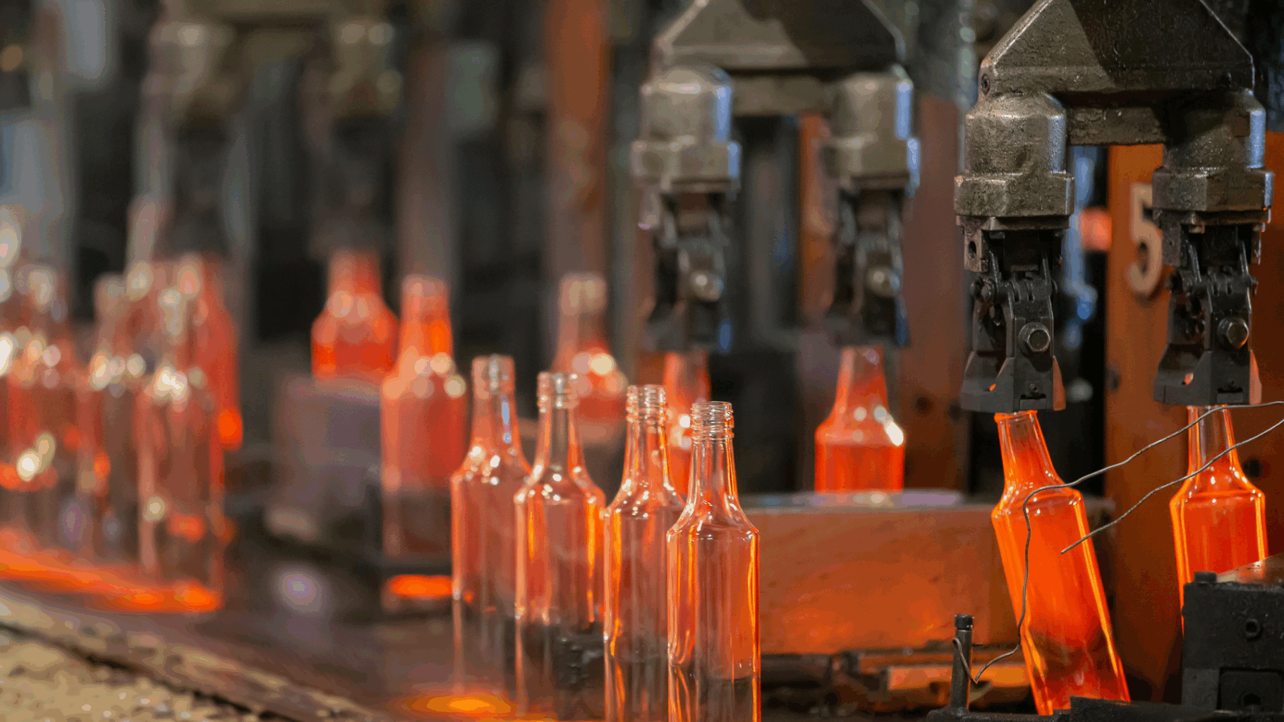 Glass bottles being manufactured on a production line as part of more sustainable glassmaking practices
