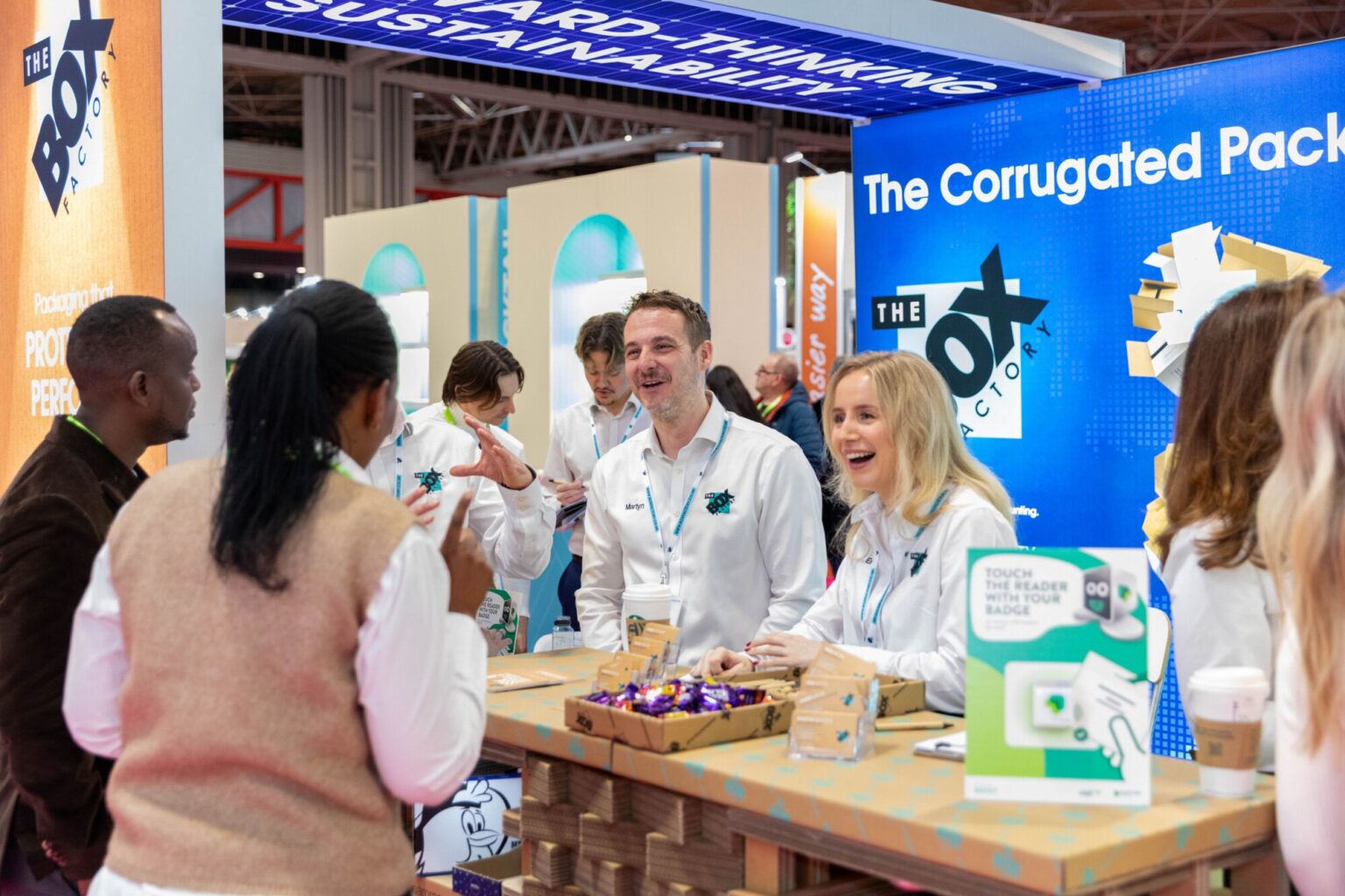Exhibitors engaging with visitors at their exhibition stand, showcasing corrugated packaging solutions at Packaging Innovations & Empack.