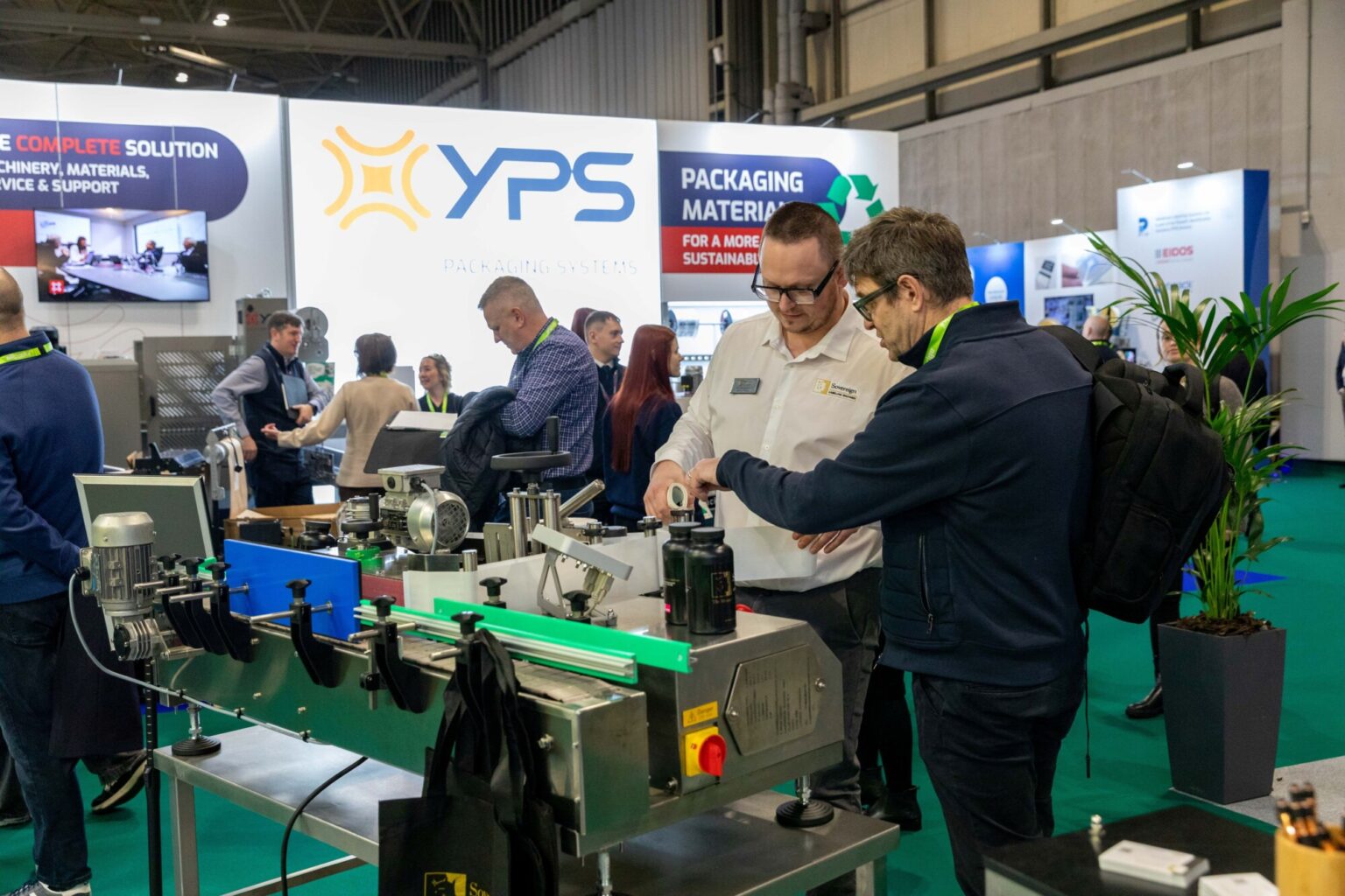 Exhibitor demonstrating packaging machinery to a visitor at Empack, with industrial equipment and packaging technology on display.