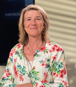 Glimlachende vrouw in bloemige blouse aan tafel