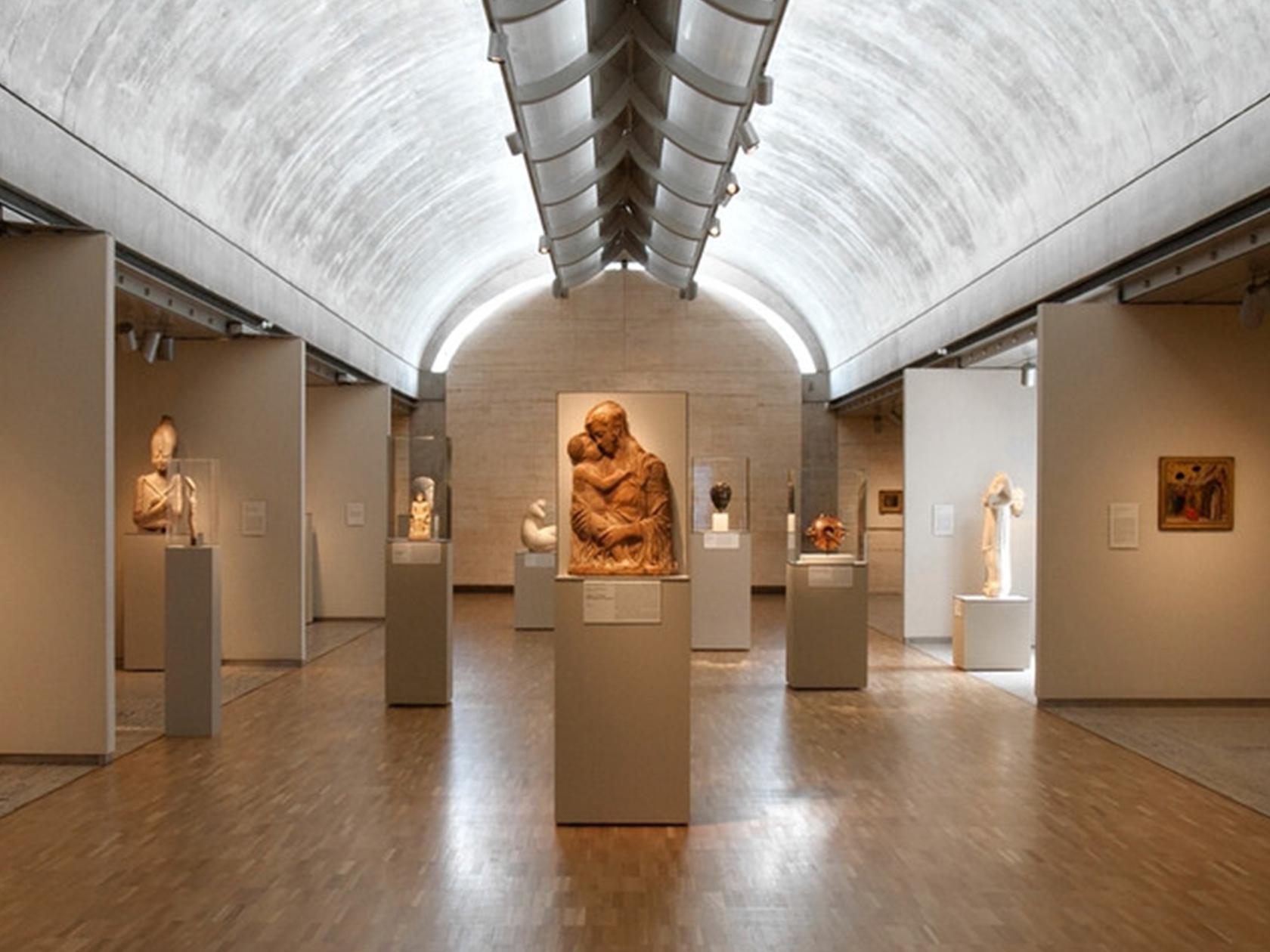 Museumzaal met sculpturen onder een gewelfd plafond