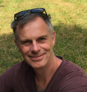 Glimlachende man met zonnebril op het hoofd in gras